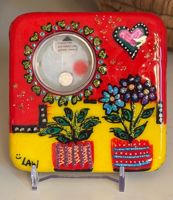 Decorative painted marble clock with colorful designs on a stand, rearview