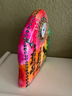 Decorative painted clock with colorful patterns on a plain background, side view