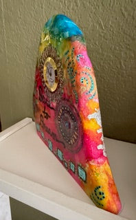 Colorful hand-painted decorative object on a white surface with a textured wall background