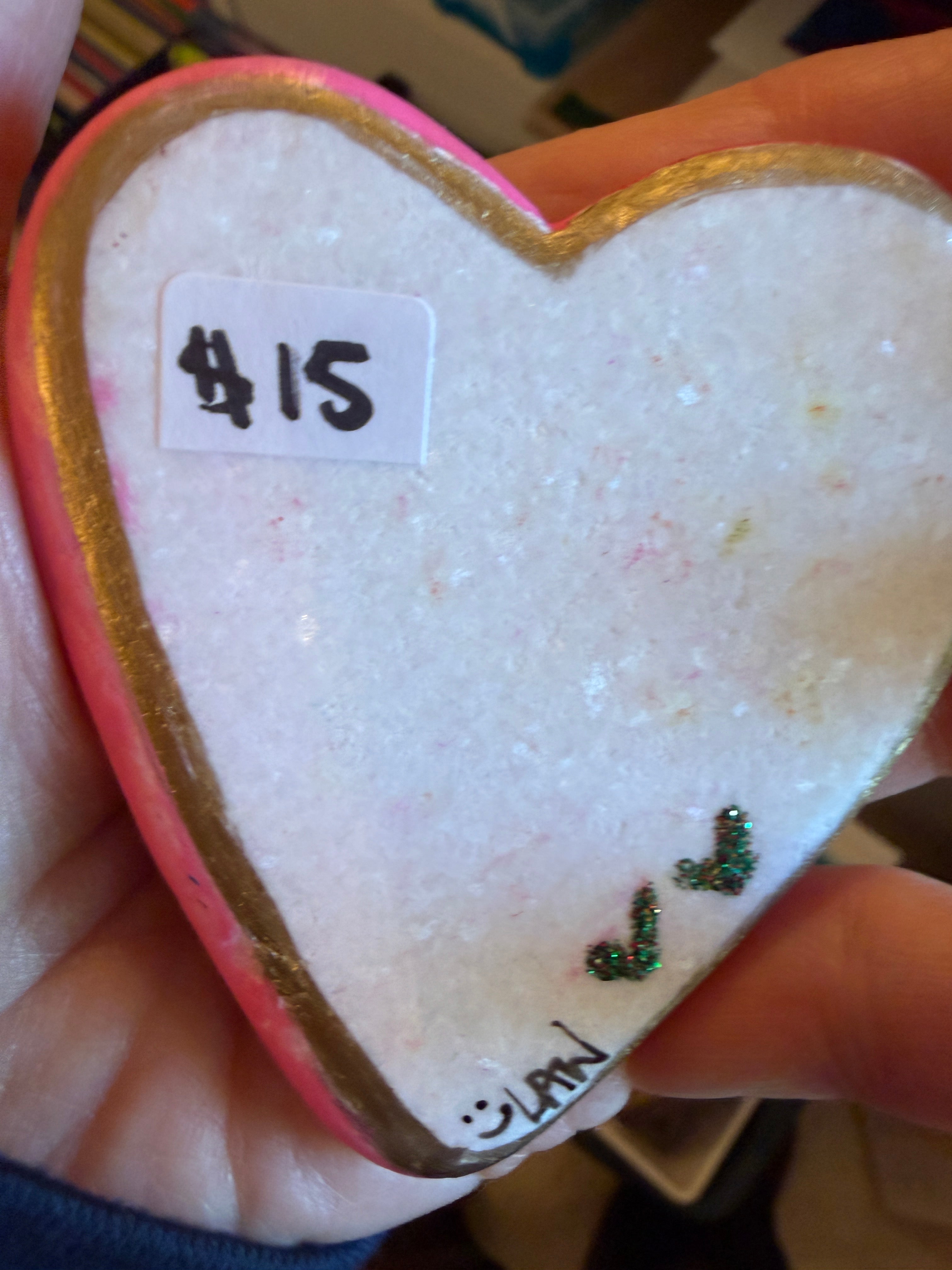 Heart-shaped stone with gold border, pink interior, and text on a blurred background