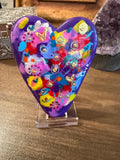 Colorful heart-shaped painted stone with floral patterns on a wooden surface