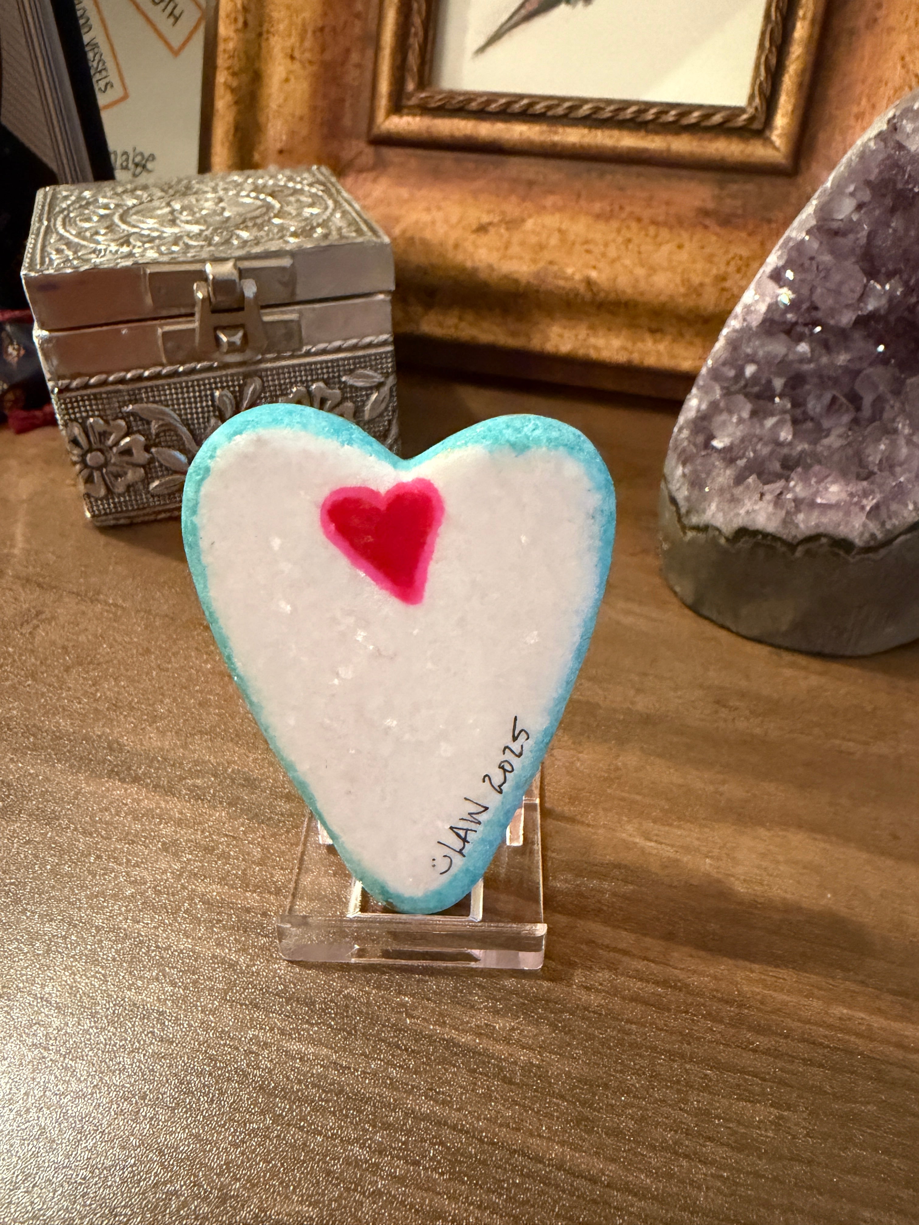 Heart-shaped painted stone with a red center on a wooden surface