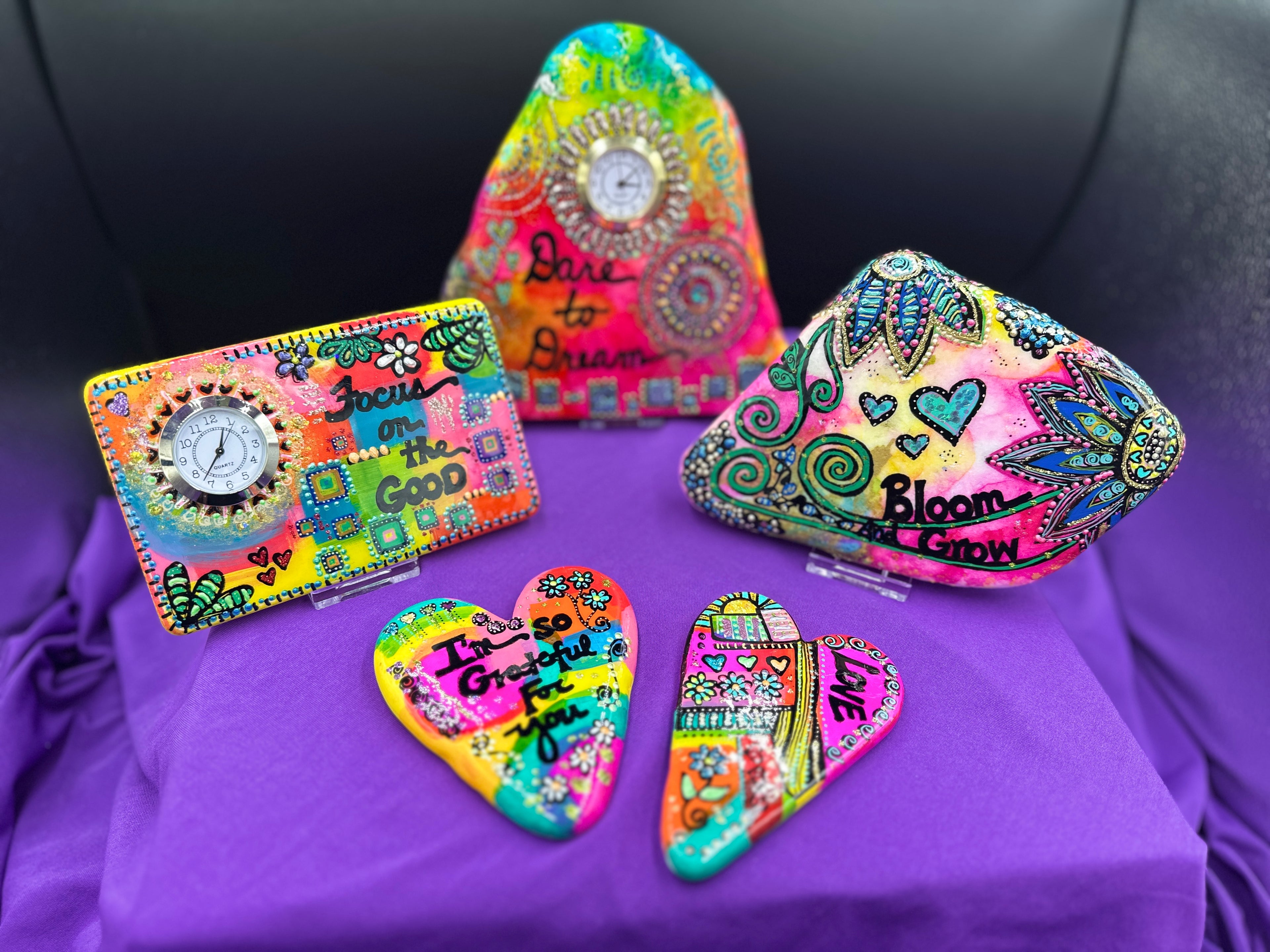 Colorful decorative stones and clocks with affirmations on a purple stand