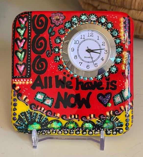 Decorative painted clock with colorful embellishments and text on a stand