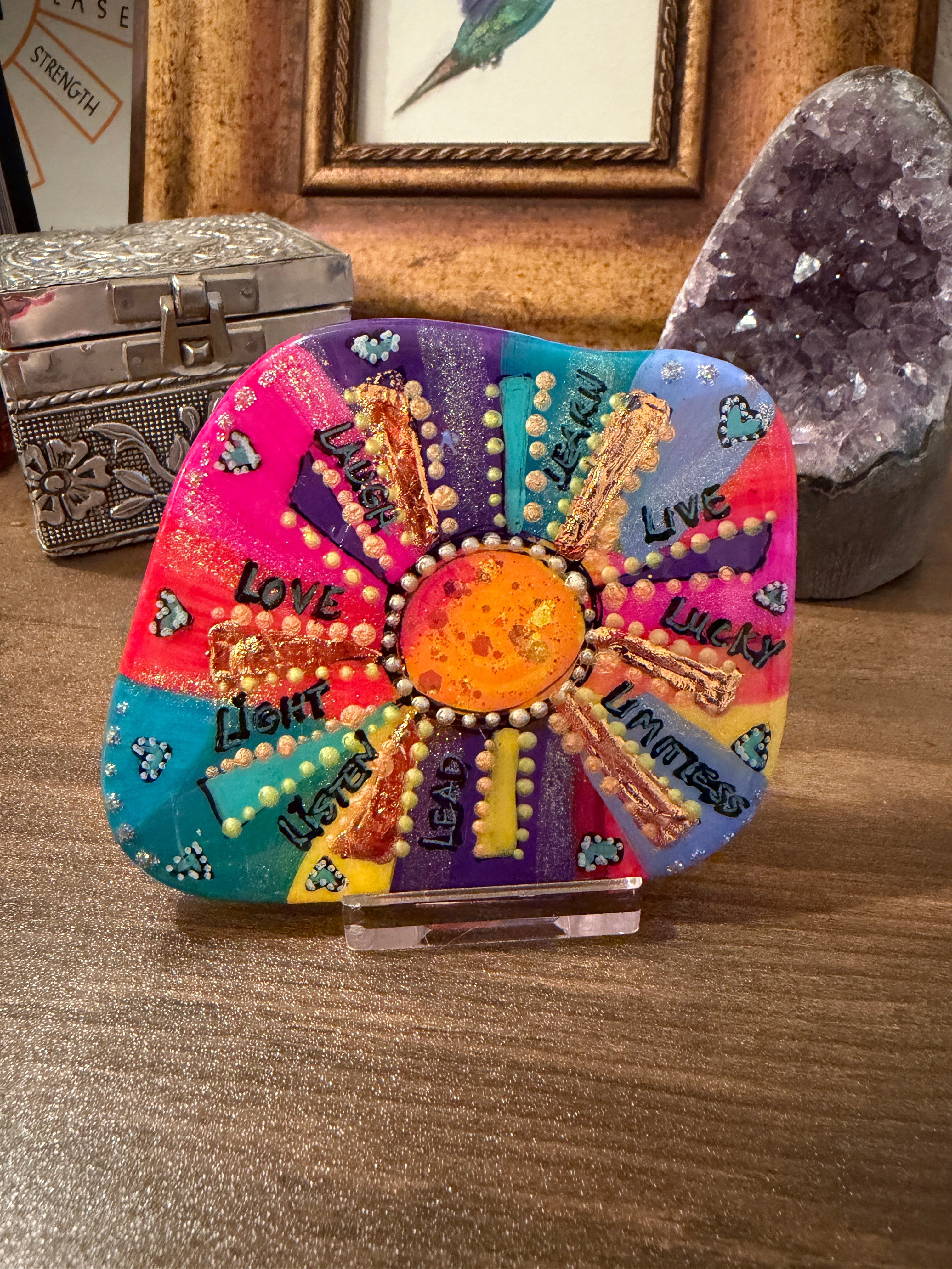 Colorful decorative handpainted stone with text on a wooden surface