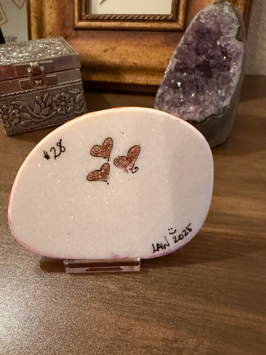 Painted stone with glitter hearts on a wooden surface